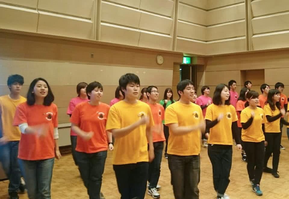 写真:ユニフォームを着てオープニングを歌う学生たち
