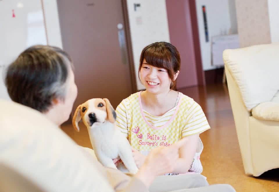 写真:女性が犬と一緒に患者さんにむかって笑顔で接している様子