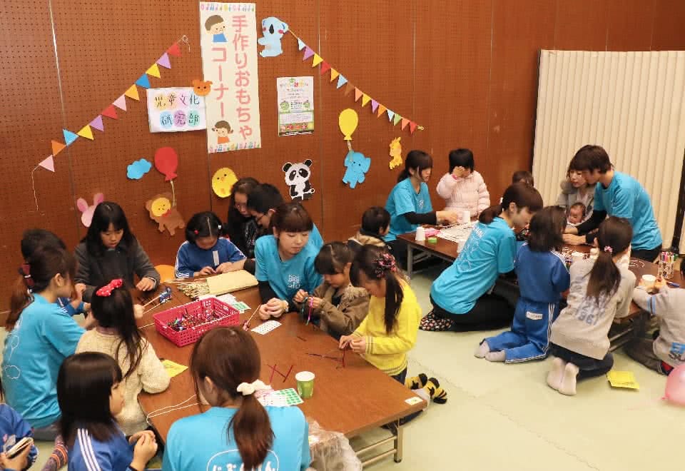 写真:地域のイベントで手作りおもちゃコーナーを開設する児童文化研究部と、そこで学生と一緒におもちゃを作る子どもたち