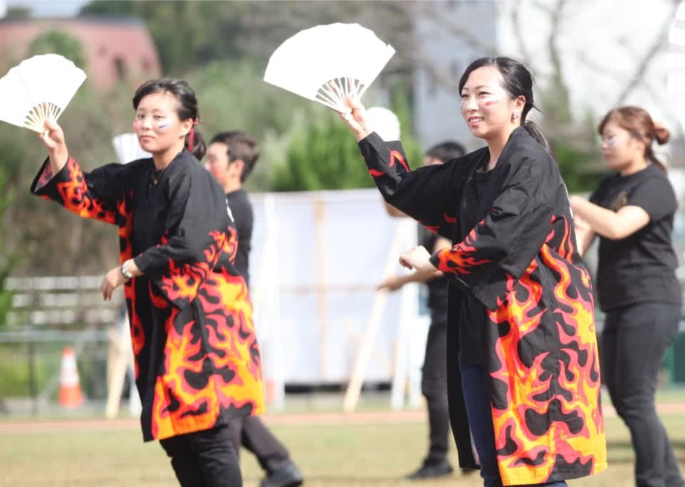 写真:県人会の活動で扇子を持って踊る学生たち