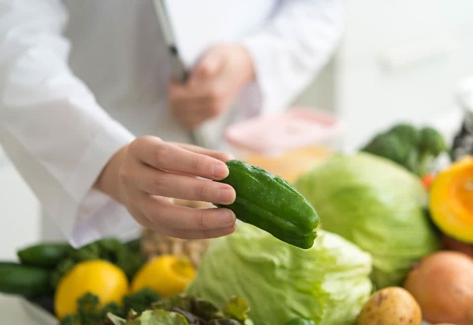 写真:沢山の野菜の中からピーマンを手に持つ様子