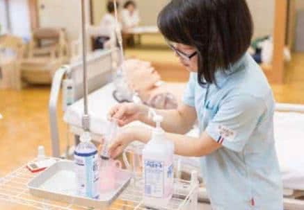 写真:介護用の器具で水を測り取る学生