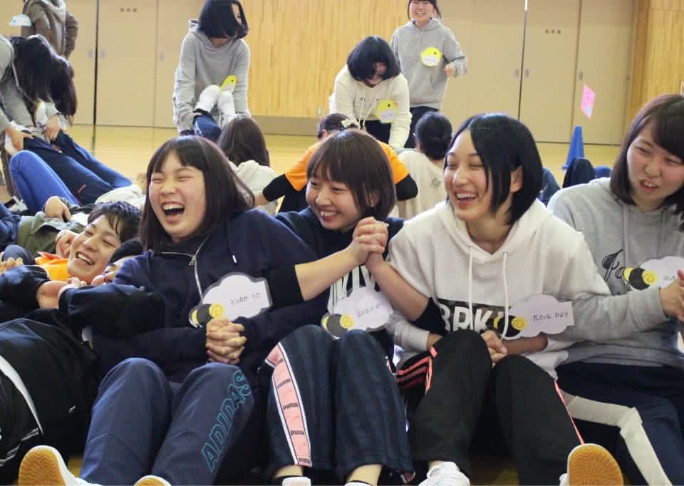 写真:体育館で手をつなぎあうレクリエーションを楽しむ学生たち
