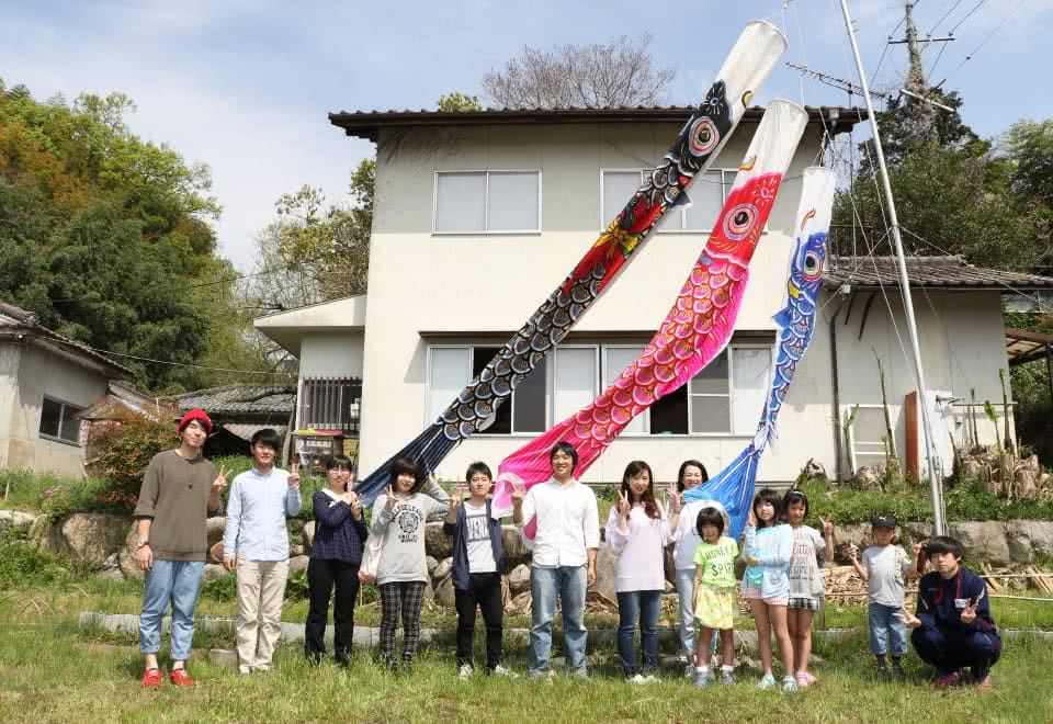 写真:じ・ば・子のおうちと鯉のぼりの前で記念撮影する子どもと高齢者、学生たち