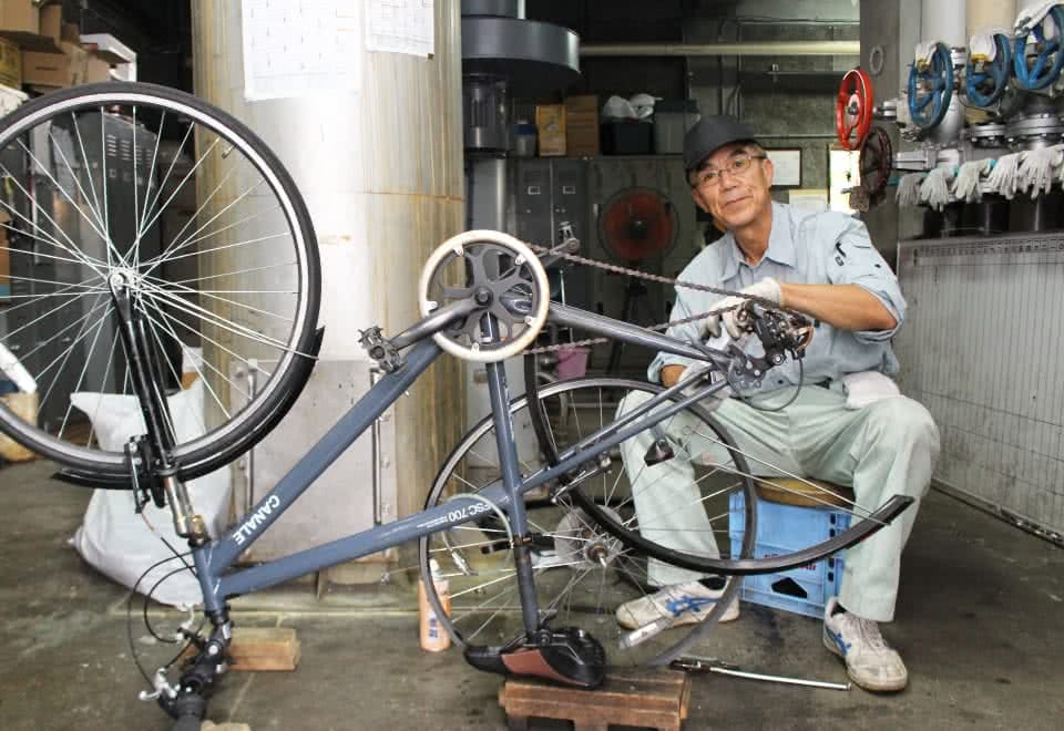 写真:自転車の修理をする男性の校務員さん