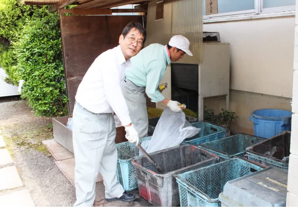 写真：ゴミ捨て場にいる二人の男性の用務員さん