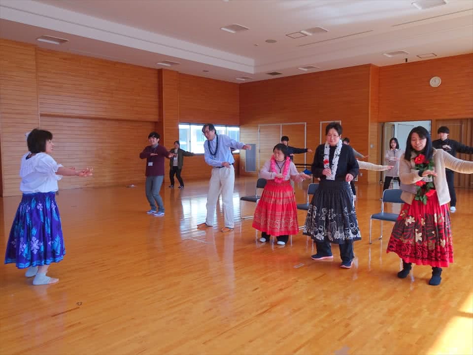 写真:カラフルな衣装を身にまとってフラダンスをする受講生と講師