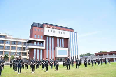 校舎を背景に、グラウンドに整列する沖縄県人会の学生と教職員