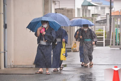 傘を差して歩く浴衣姿の学生たち