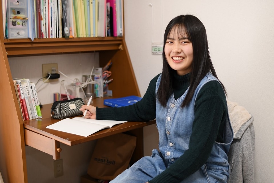 写真：机の前で、笑顔を向けるMさん