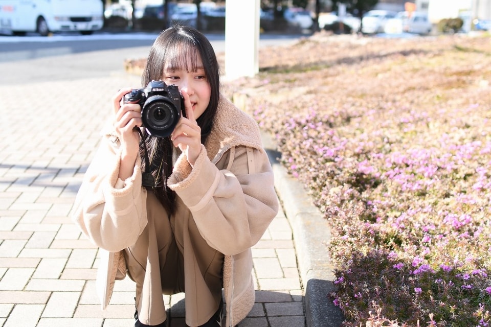 写真：しゃがんでカメラを構えるMさん