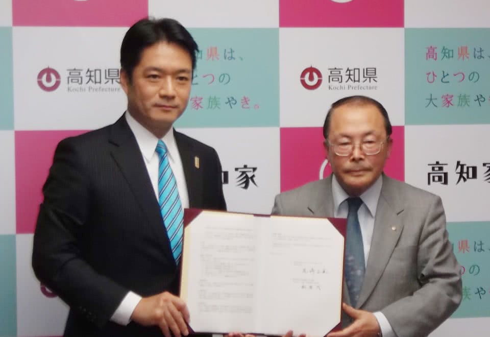 写真：高知県との締結式で協定書を手に持っている尾﨑正直高知県知事と船盛茂学長