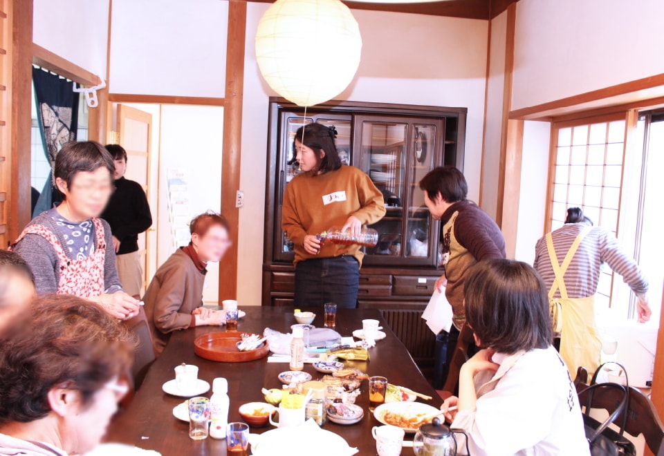 写真：食卓を囲んで会話するおあしすカフェ参加者と学生たち