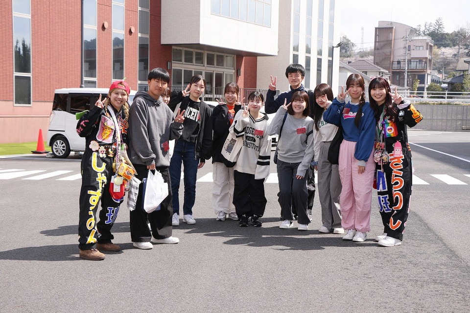 写真:学校の前でピースサインをして笑顔で並ぶ学生グループ