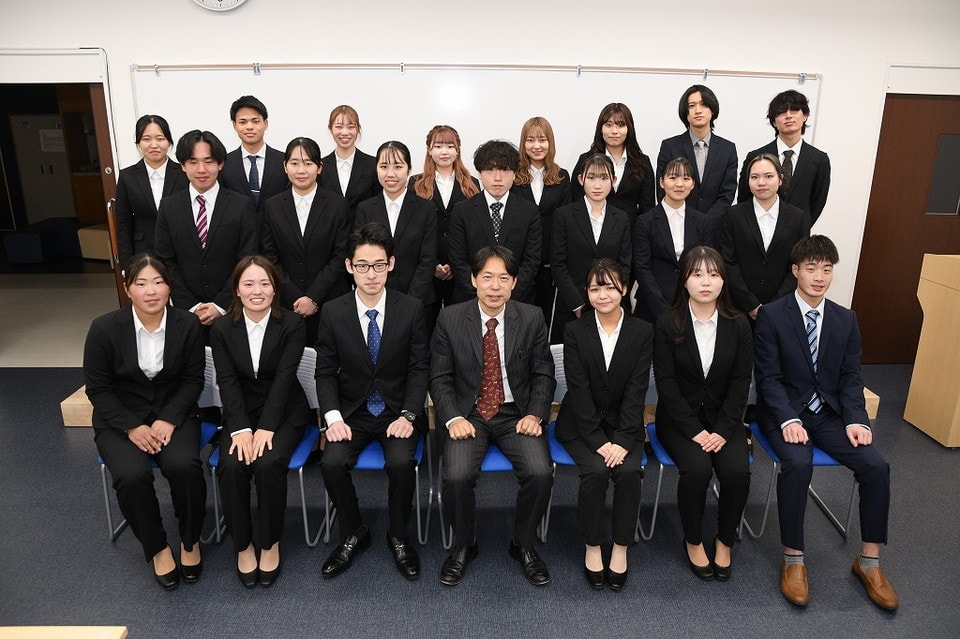 写真:スーツ姿で集合写真を撮る学生たちと教員