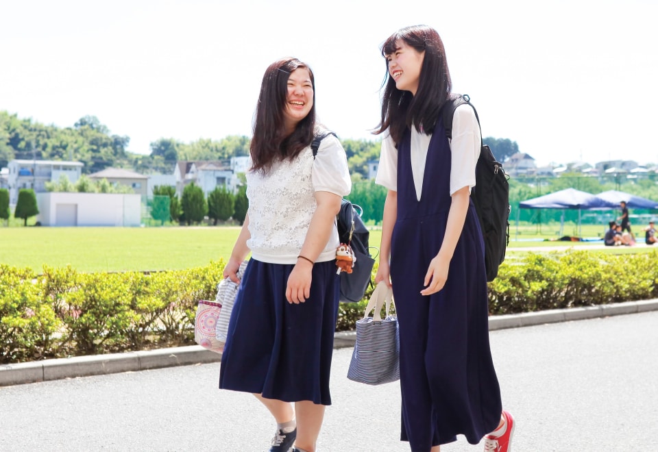 笑顔で会話をしながら歩く2人の女子学生