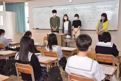 高校生の前でスピーチをする大学生