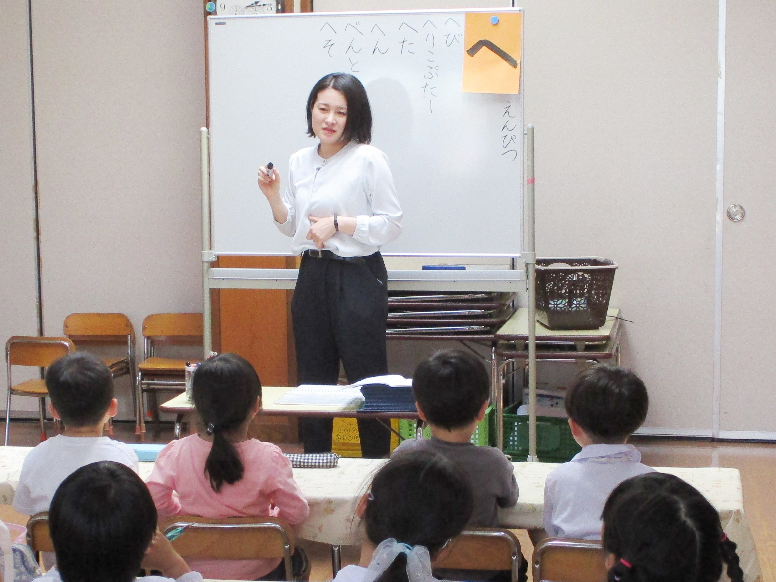 西尾先生と、席に座って授業を受けている園児たち写真