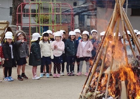 写真：とんどの行事で、竹でできたやぐらを燃やしているところを見ている園児たち