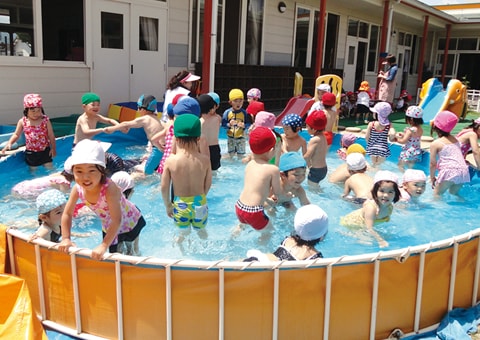 写真：園庭に儲けた簡易プールでプールあそびを楽しむ園児たち