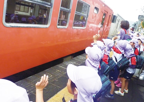 写真：列車体験で列車に手を振るホームにいる園児たち
